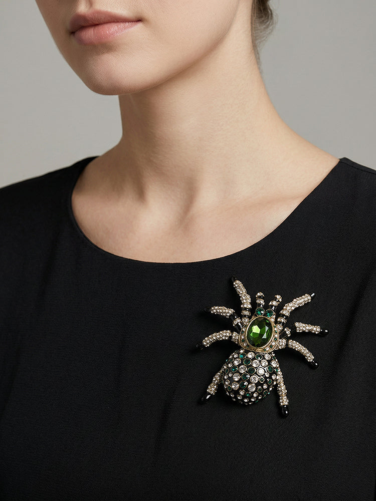 Green spider brooch pinned to black top